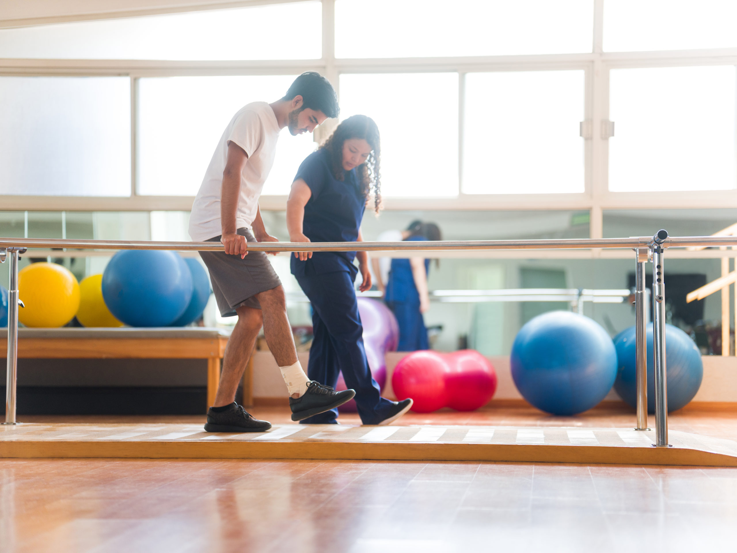 Athletic patient walking in parallel bars