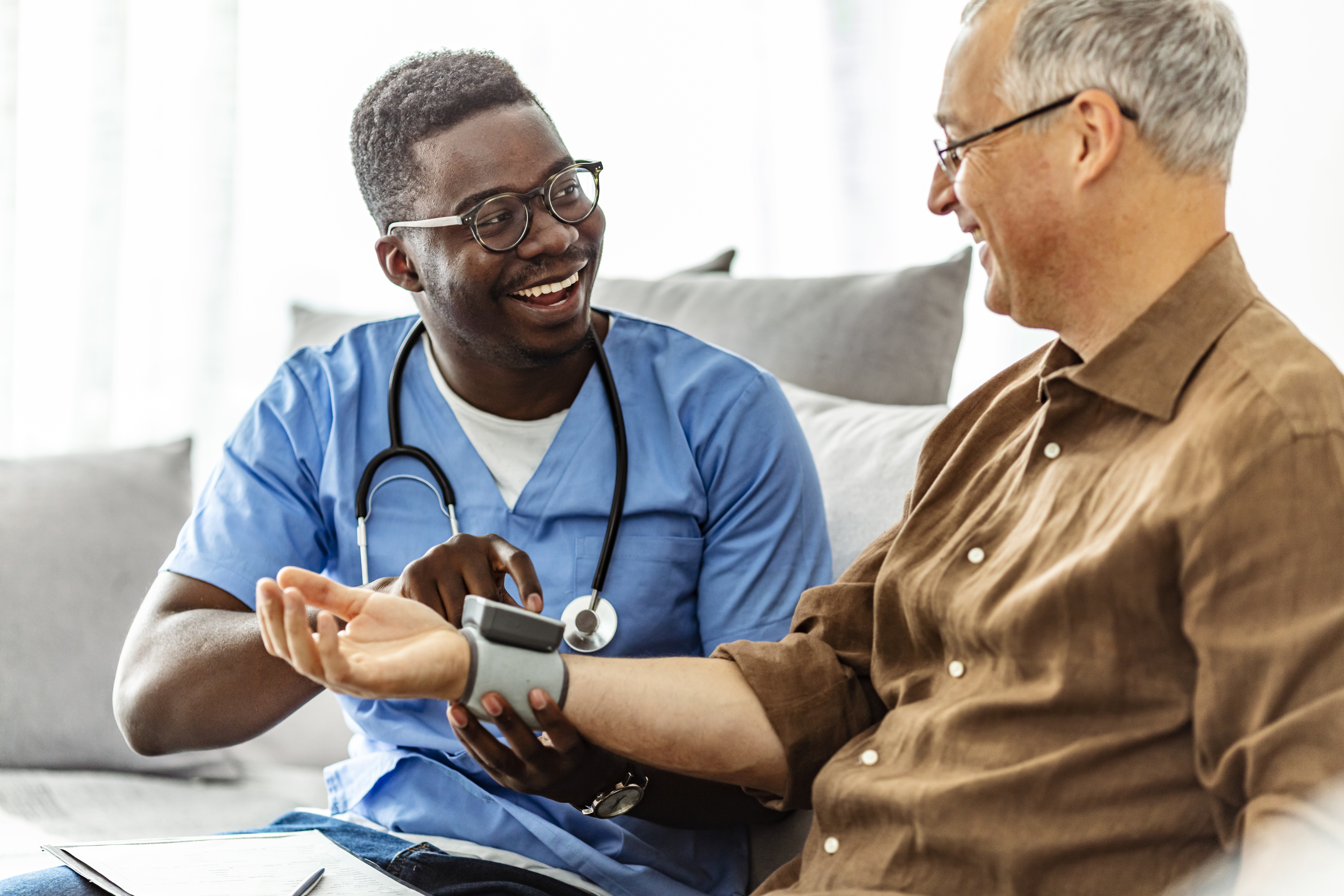 Caretaker measuring mature man's blood pressure