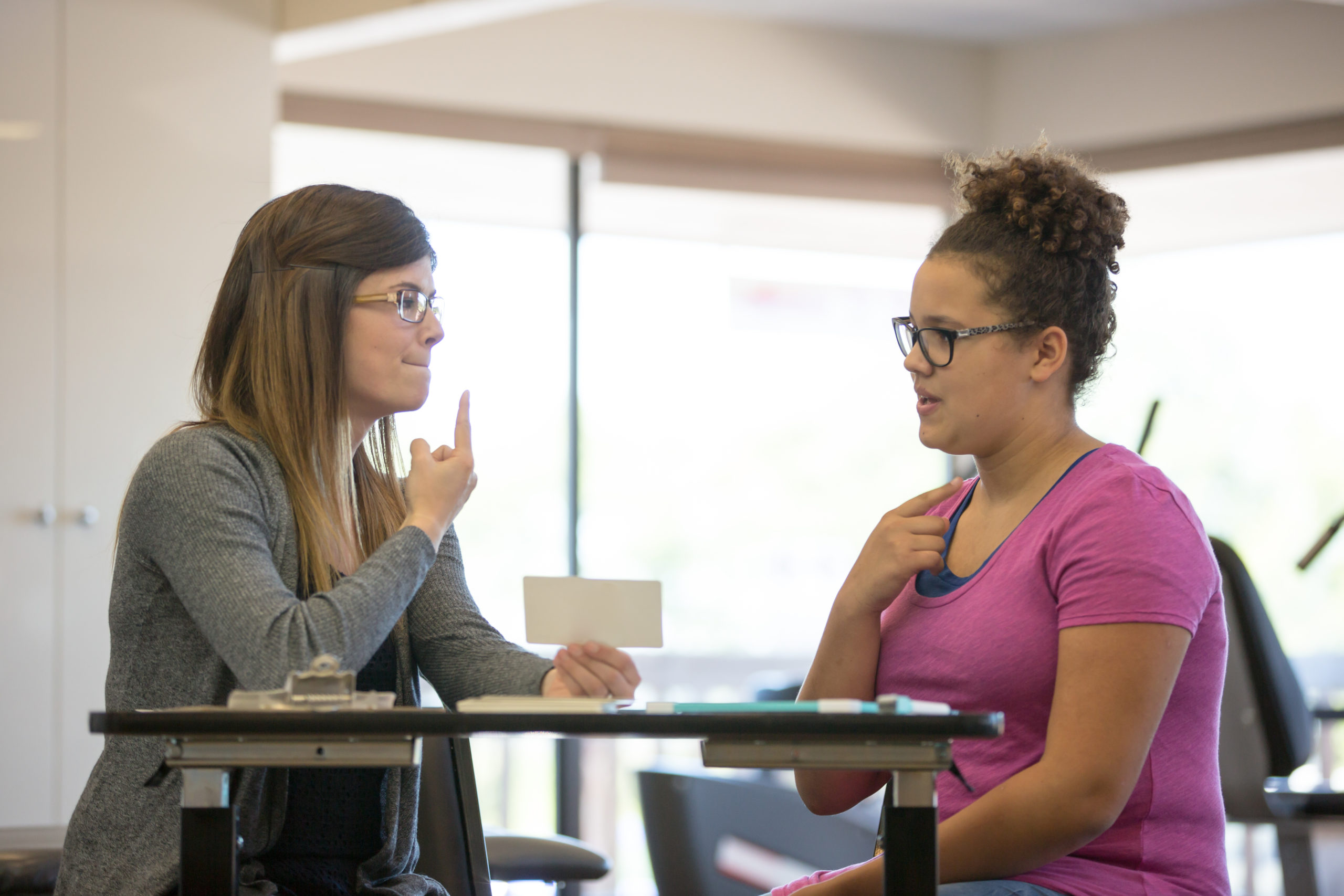 Female speech therapist helping a teenage patient inside of a clinic