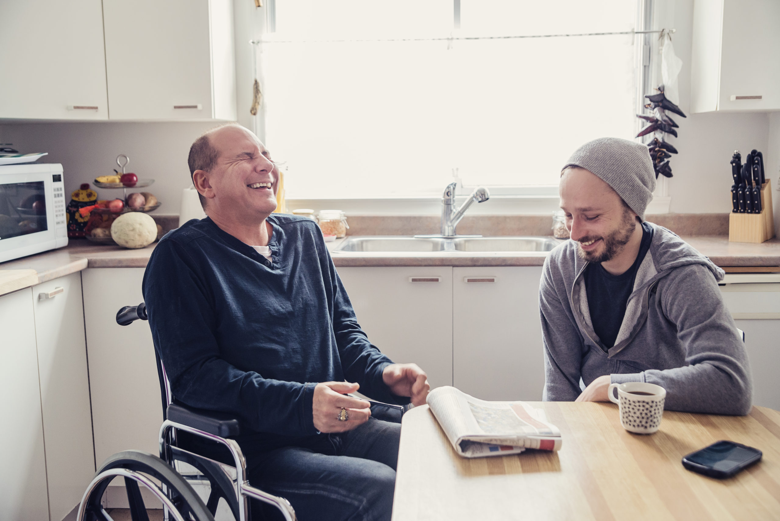 Man visiting a disabled friend and having a coffee.