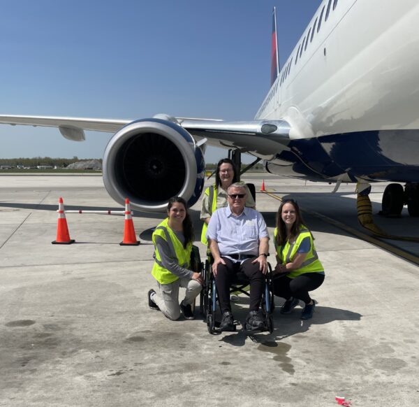 Patient Denver with Kelsey occupational therapist and LeeAnn recreation therapist in front of an airplane.
