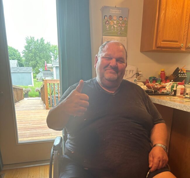 Patient Forest giving the thumbs up in his kitchen