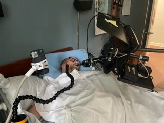 Patient Tracey on his computer using an adaptive mouse joystick he operates with his mouth, while still lying flat in bed