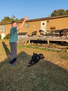 Patient Timmy throwing a ball for his black lab dog.