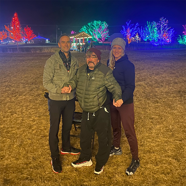 Patient Jeff during his last treatment session out walking to look at Christmas lights with his PT Spencer (left) and RT Pam (right).