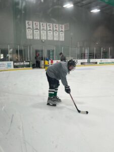 Patient William playing hockey in a skating rink.