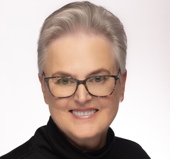Headshot of patient Maureen wearing black glasses and black turtleneck with short silver hair.