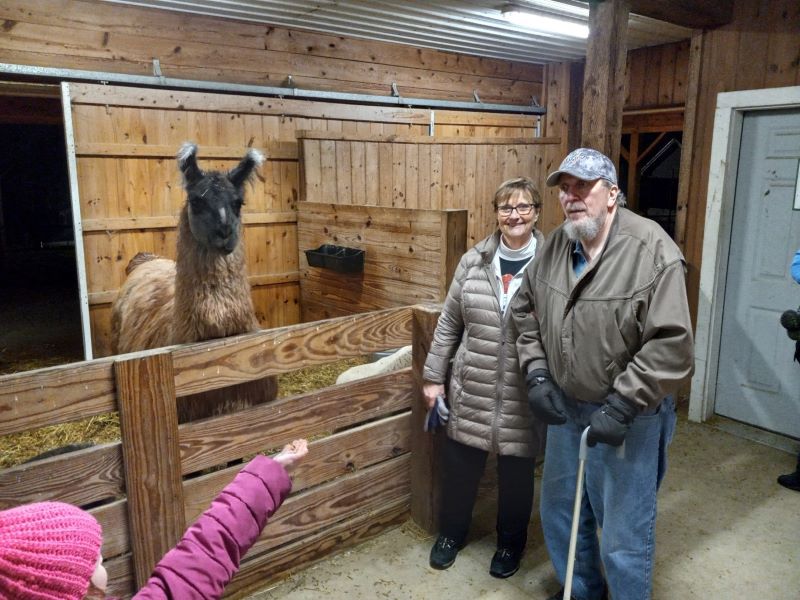 Patient Kevin and his wife standing in a barn next to an alpaca.