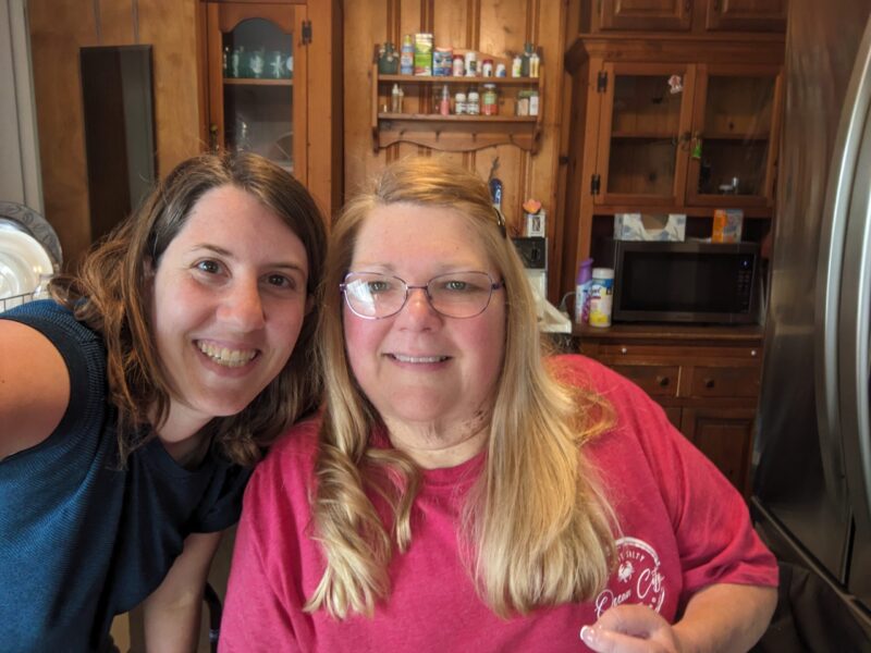Audra K. is a blonde woman, who is sitting next to her therapist, they are both smiling.