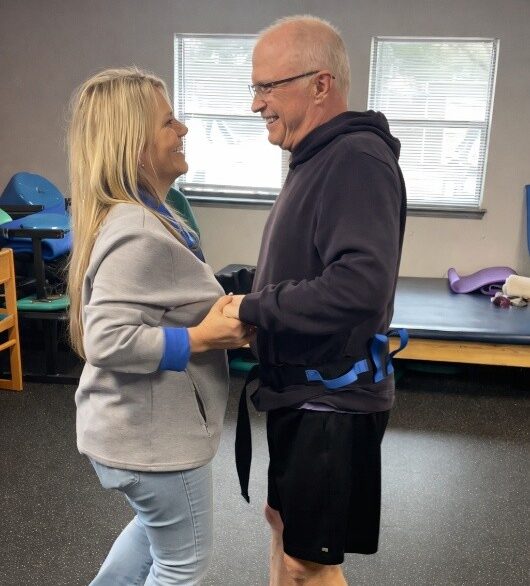 Brett is dancing with his wife. they are both look at each other and smiling.