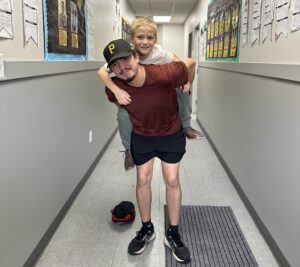 small child smiling while an adult carries him on his back. 