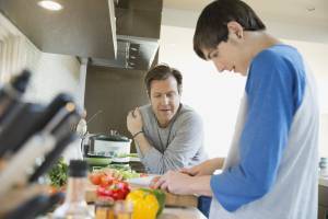 Father teaching son to cook in kitchen
